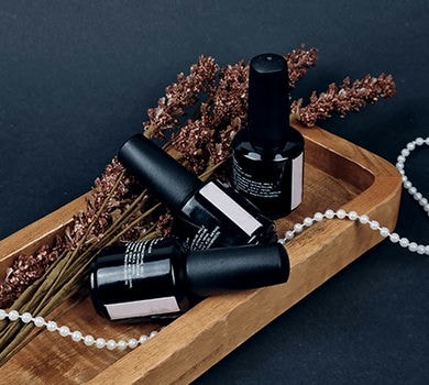 Three bottles of nail base inside a wooden tray with few decorations around